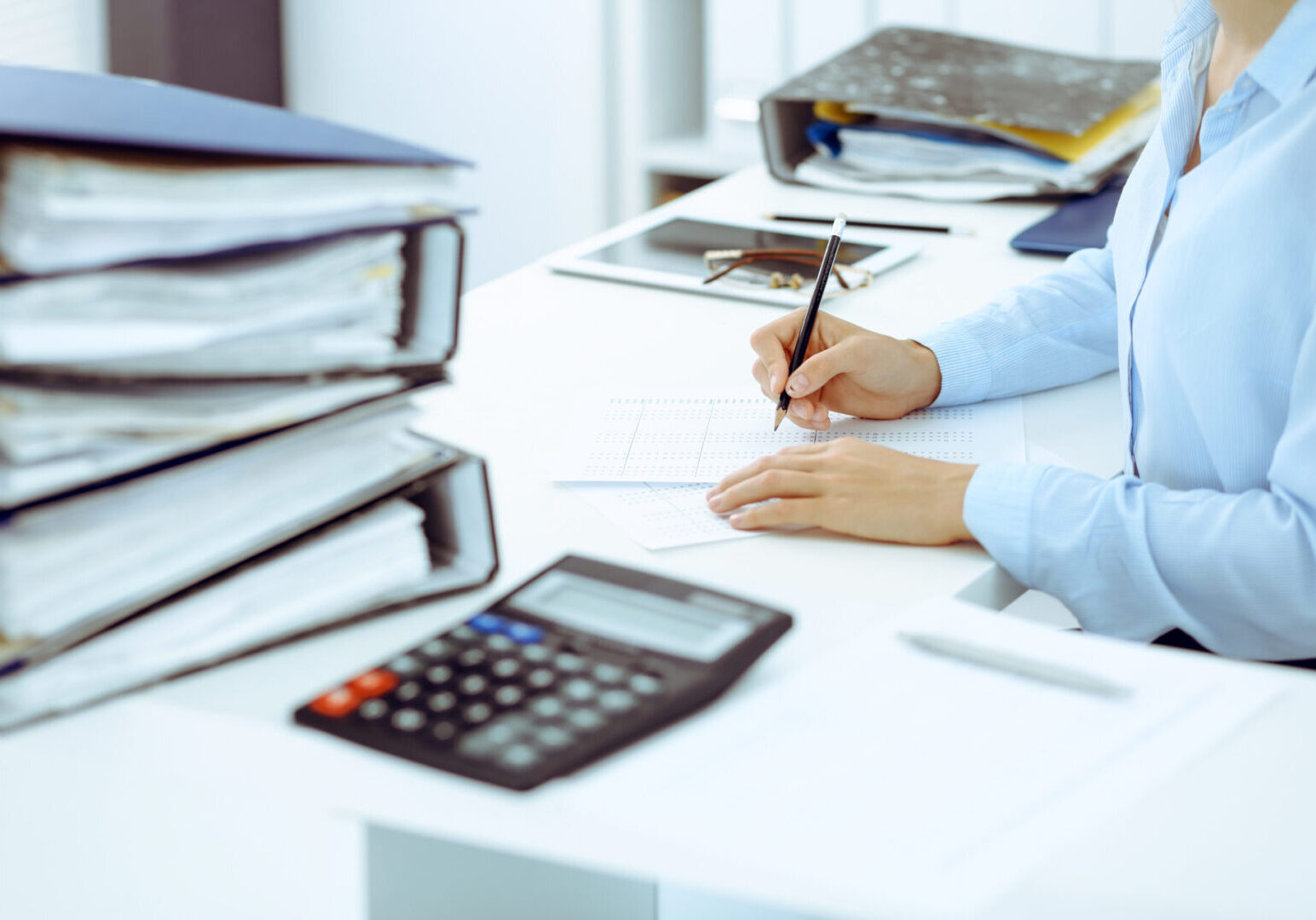 Unknown female bookkeeper or financial inspector calculating or checking balance, making report, close-up. Internal Revenue Service at work with financial document. Tax and audit concept.